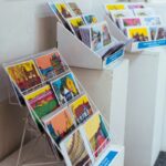 Various colorful illustrated postcards displayed on white stands