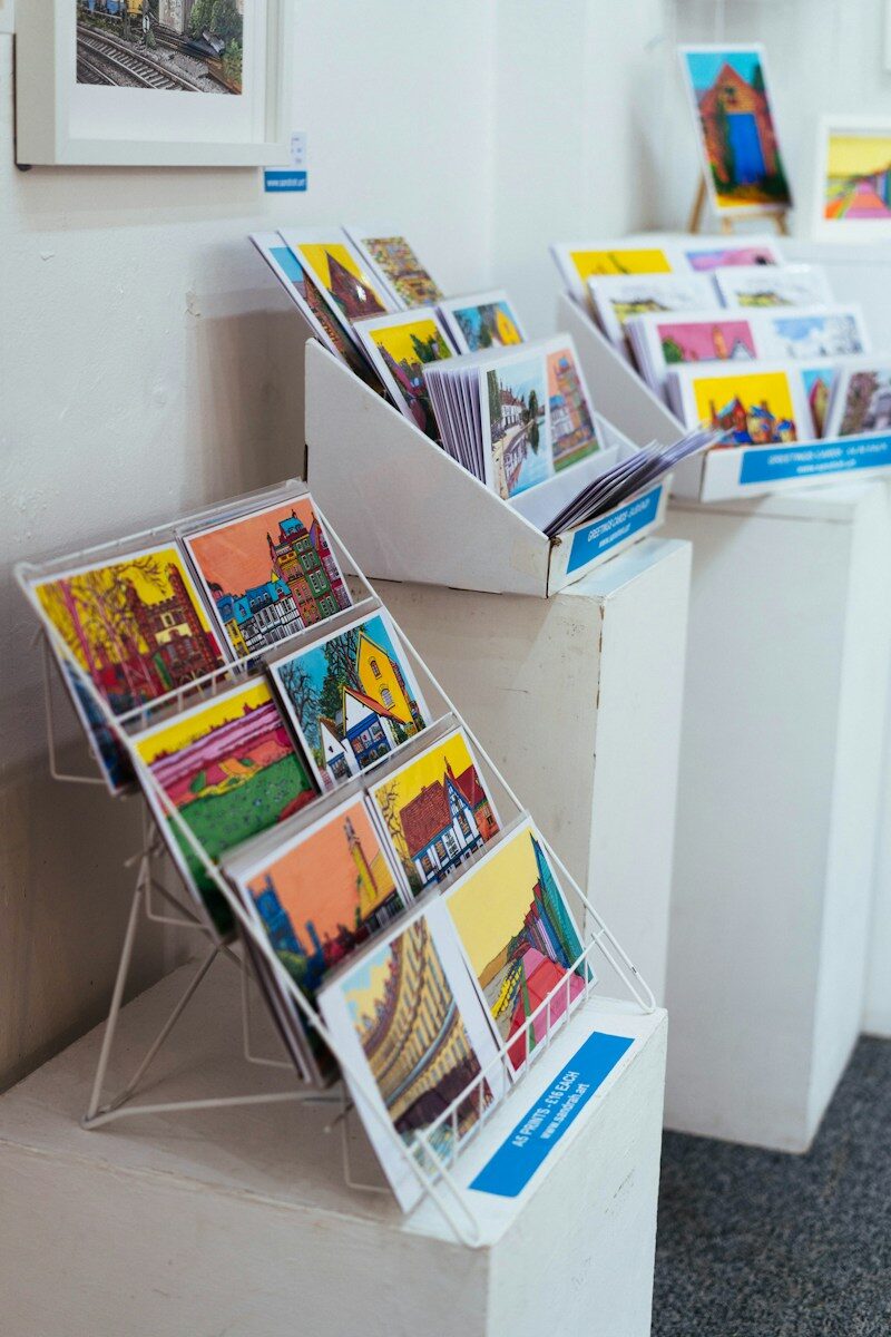 Various colorful illustrated postcards displayed on white stands